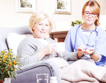 caregiver helping old woman to take her medicine