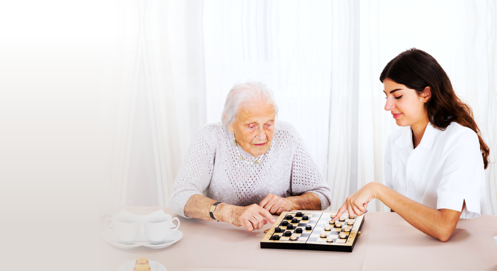 old woman and caregiver playing chess